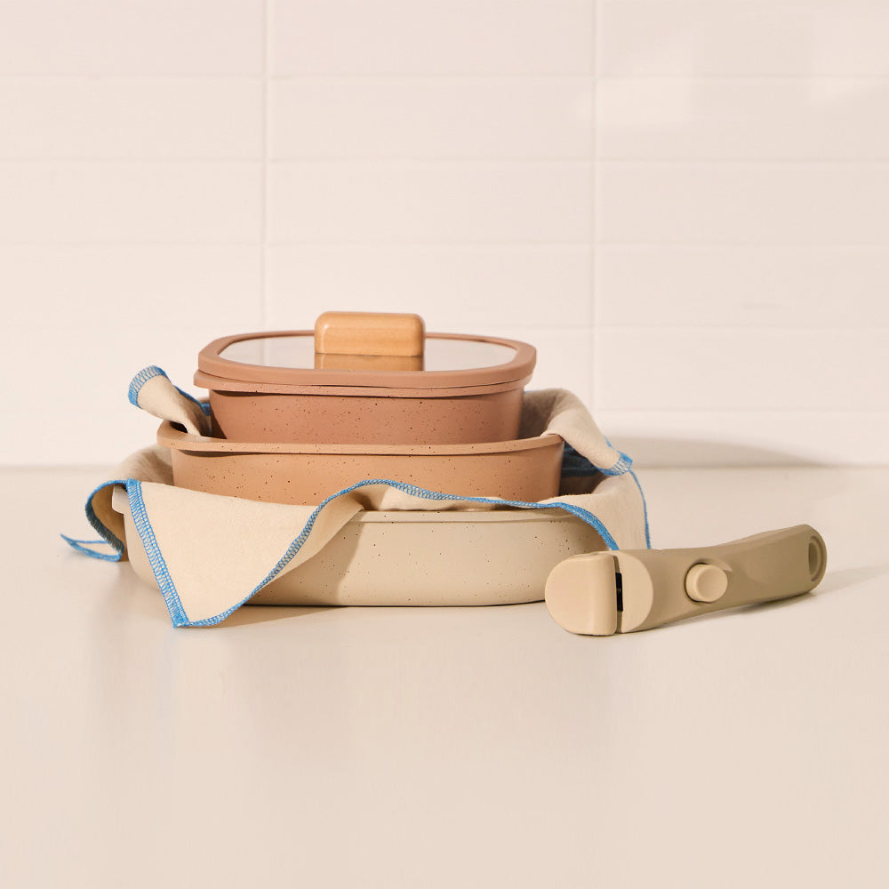 Stacked terracotta and beige containers wrapped in cloth, accompanied by a detachable handle.