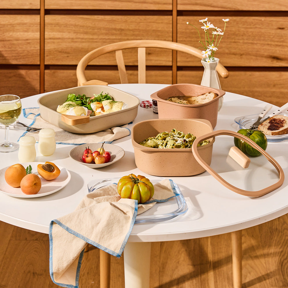 Dining table setup with terracotta containers serving pasta, salad, and other dishes.