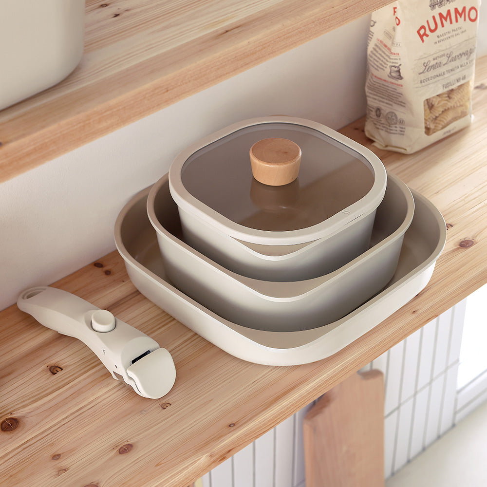 A stack of square storage containers with glass lids and a detachable handle, displayed on a wooden shelf.
