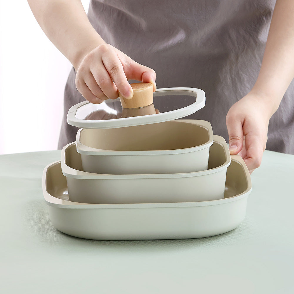 A person placing a glass lid with a wooden handle onto a stack of nested square containers.