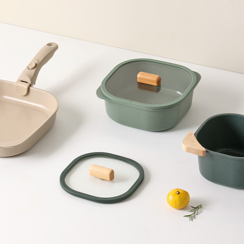 Green and beige square containers with glass lids and a beige skillet with a detachable handle.